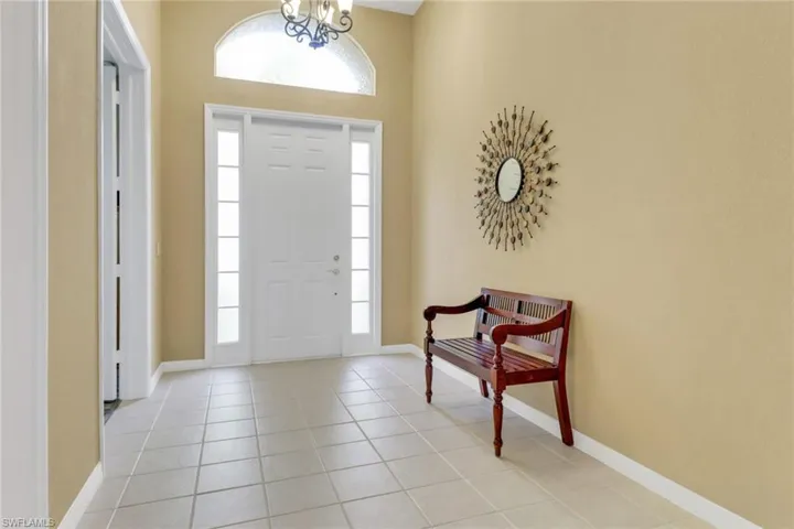 Foyer featuring healthy amount of natural light, light tile patterned floors, and baseboards