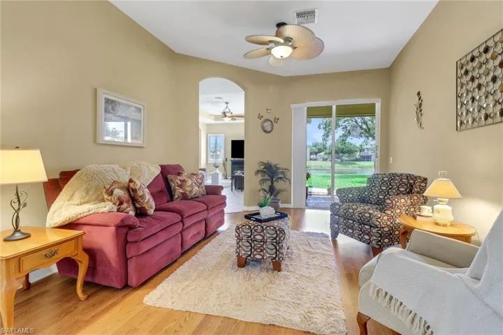 Living room with ceiling fan, wood finished floors, and arched walkways