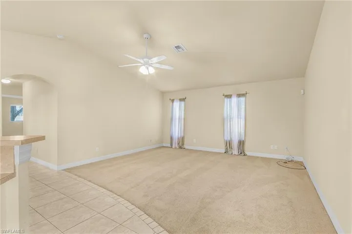 Spare room with ceiling fan, vaulted ceiling, light tile patterned floors, and plenty of natural light