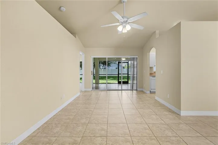 Tiled empty room with vaulted ceiling and ceiling fan