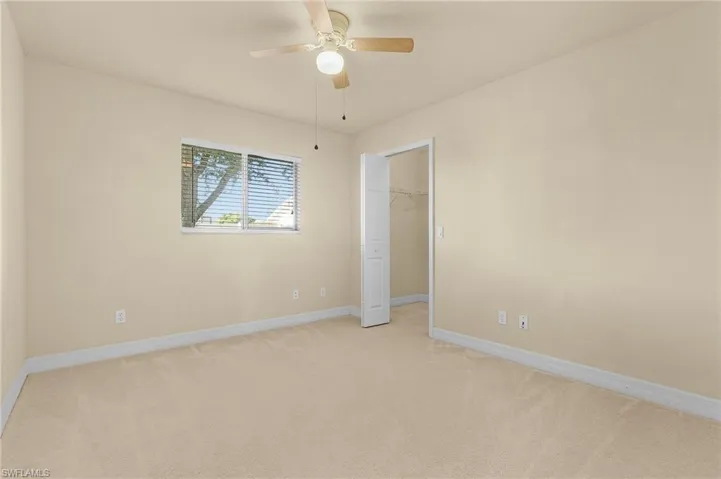 Unfurnished bedroom featuring a spacious closet, light carpet, a closet, and ceiling fan