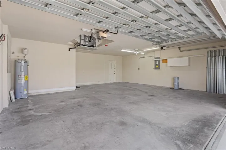 Garage featuring electric water heater and a garage door opener