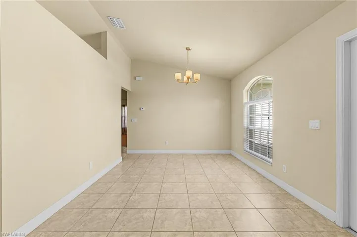 Empty room featuring high vaulted ceiling, a chandelier, and light tile patterned floors