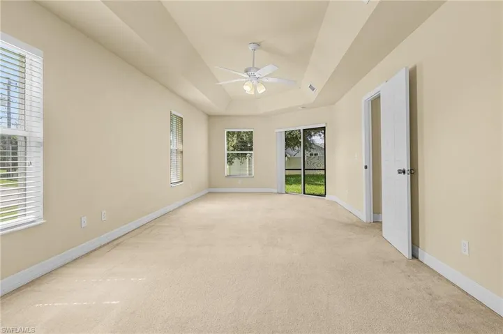 Carpeted empty room featuring ceiling fan and a tray ceiling