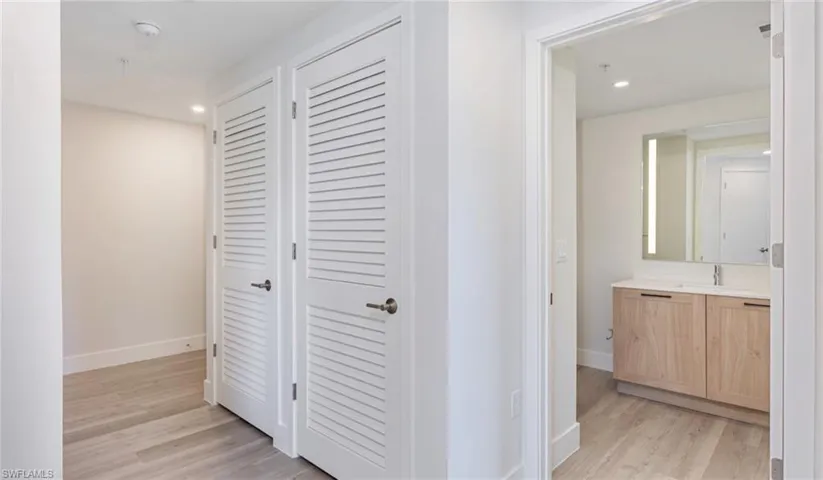 Hallway featuring recessed lighting, light wood finished floors, baseboards, and a sink