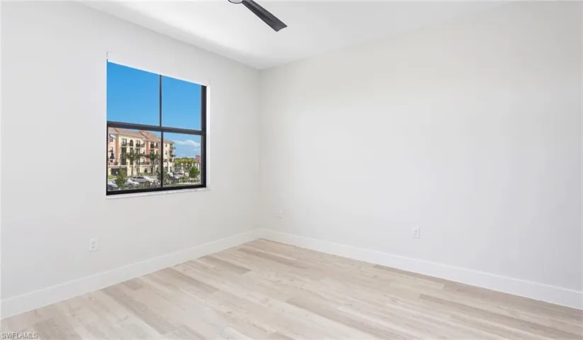 Spare room with ceiling fan, light wood-style floors, and baseboards