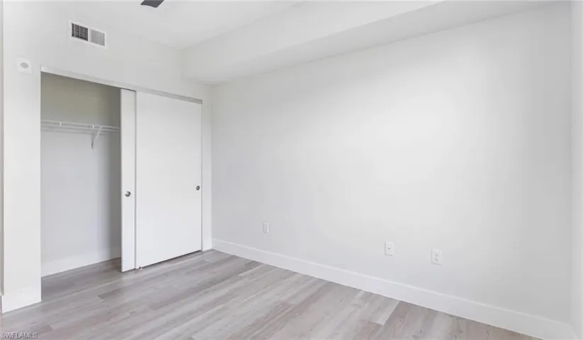 Unfurnished bedroom featuring light wood-style flooring, a closet, baseboards, and visible vents