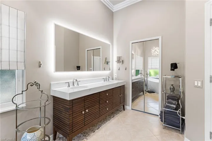 Freestanding dual vanity with a back lit mirror. Walk in custom closet is thru the mirrored door.