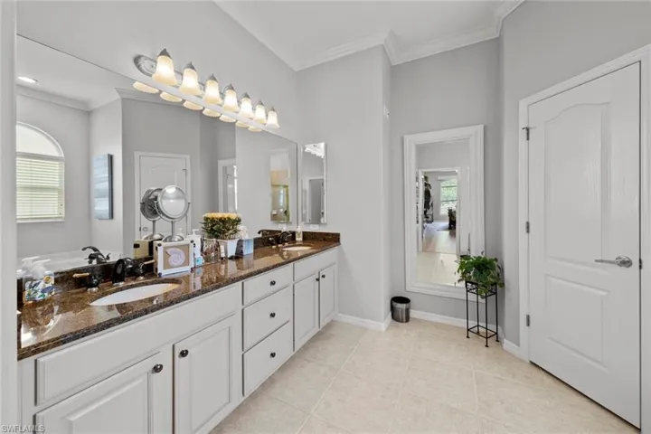Bathroom with tile floors, dual sinks, crown molding, and oversized vanity