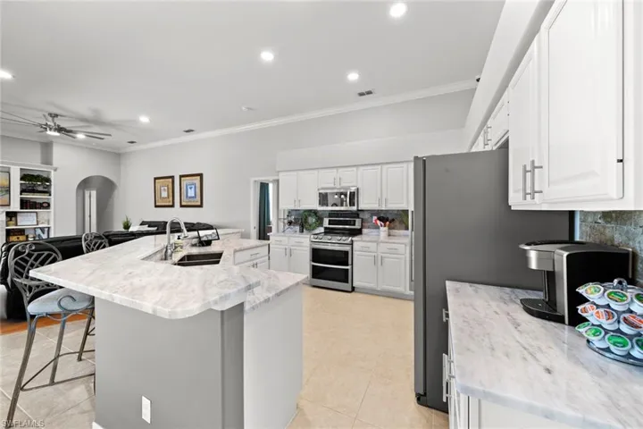 Kitchen with stainless steel appliances, sink, white cabinetry, and a breakfast bar area