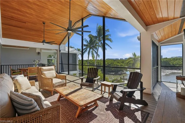 Sunroom / solarium featuring wood ceiling, vaulted ceiling, outdoor lounge area, plenty of natural light, and hardwood / wood-style floors - Virtually Edited Image