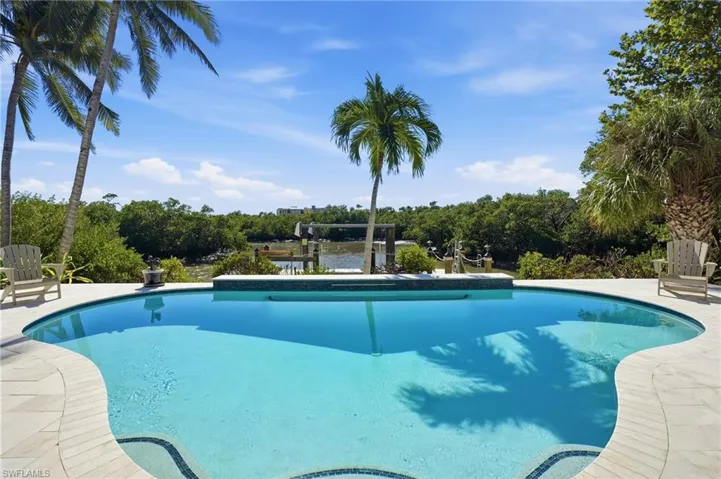 Outdoor pool with a patio, boat lift, view of wooded area, and a boat dock - Virtually Edited Image