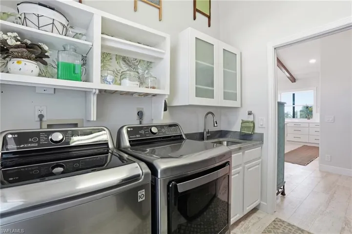 Laundry area with light wood finished floors, independent washer and dryer, recessed lighting, and cabinet space - Virtually Edited Image