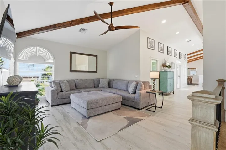 Living room with light wood-style floors, beamed ceiling, ceiling fan, recessed lighting, and high vaulted ceiling - Virtually Edited Image