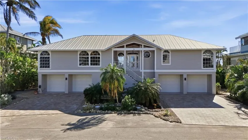 Coastal home with a garage, stairway, and decorative driveway - Virtually Edited Image