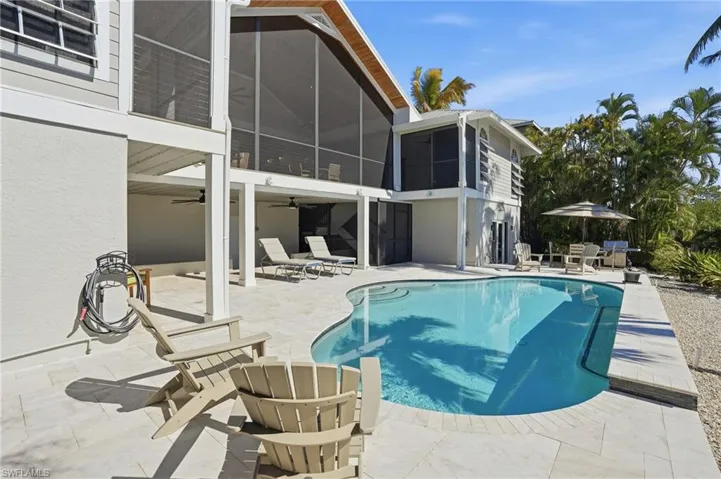 Outdoor pool featuring a sunroom, a patio area, and outdoor dining space - Virtually Edited Image