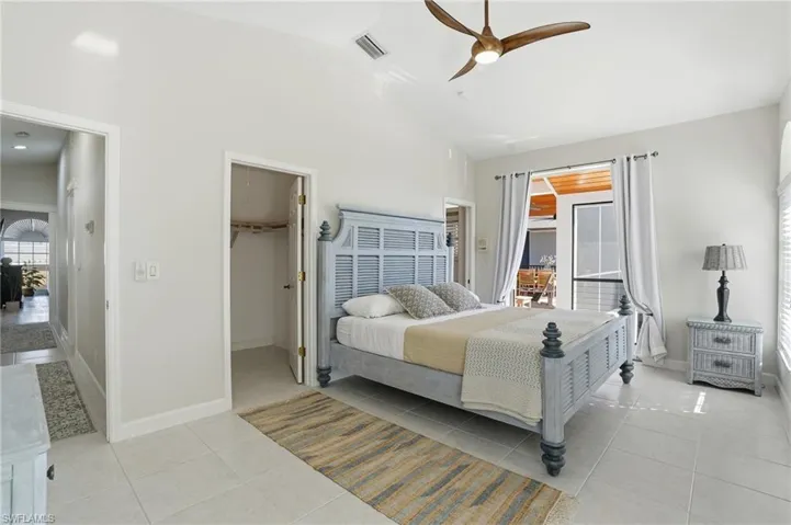 Bedroom with a walk in closet, lofted ceiling, light tile patterned floors, and ceiling fan - Virtually Edited Image