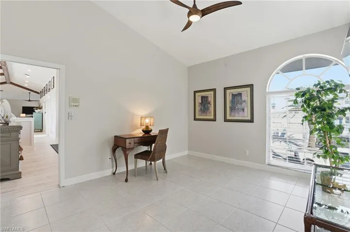 Office space featuring a ceiling fan, plenty of natural light, light tile patterned flooring, and high vaulted ceiling - Virtually Edited Image