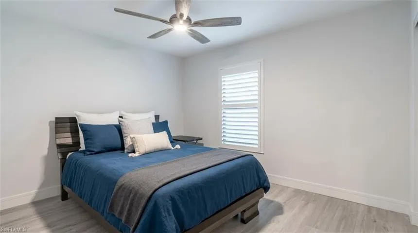 Wood-finish flooring, plantation shutters, and a ceiling fan with integrated lighting