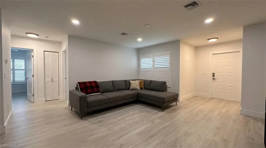 Expansive interior with light wood-finish flooring, recessed lighting, and plantation shutters