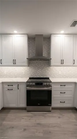 Modern kitchen featuring white shaker cabinetry, stainless steel range and hood, white countertops, and a white mosaic tile backsplash