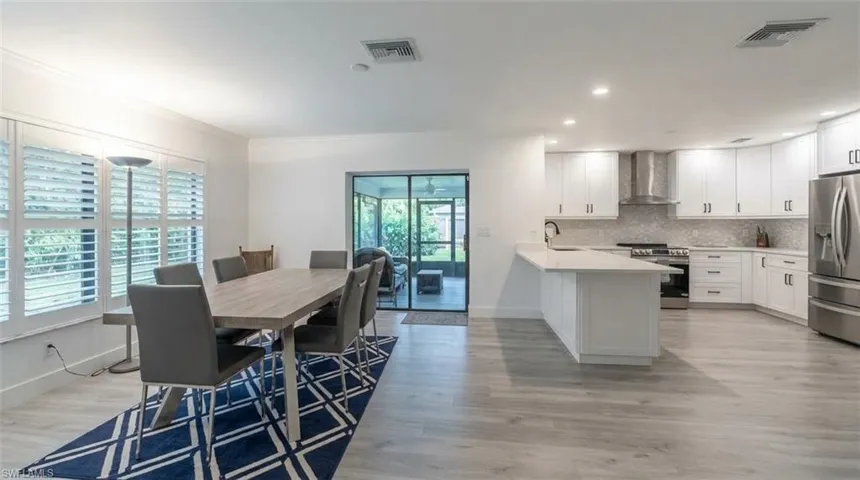 Sleek kitchen with stainless steel appliances, white cabinetry, and a light-toned countertop island