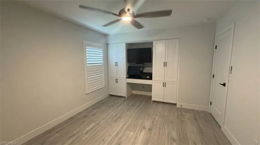 Wood-finish flooring, built-in cabinetry with integrated desk space, ceiling fan, and plantation shutters