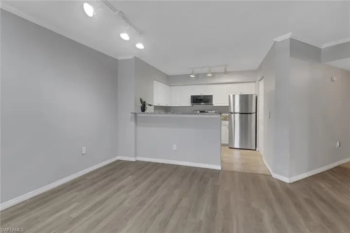 Kitchen with a peninsula, white cabinets, freestanding refrigerator, light wood-style flooring, and crown molding