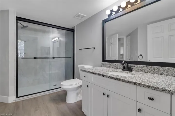 Full bath with a shower stall, vanity, and light wood finished floors