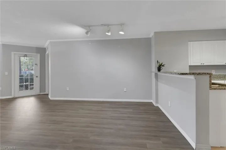 Unfurnished dining area featuring crown molding, light wood-style floors, and rail lighting