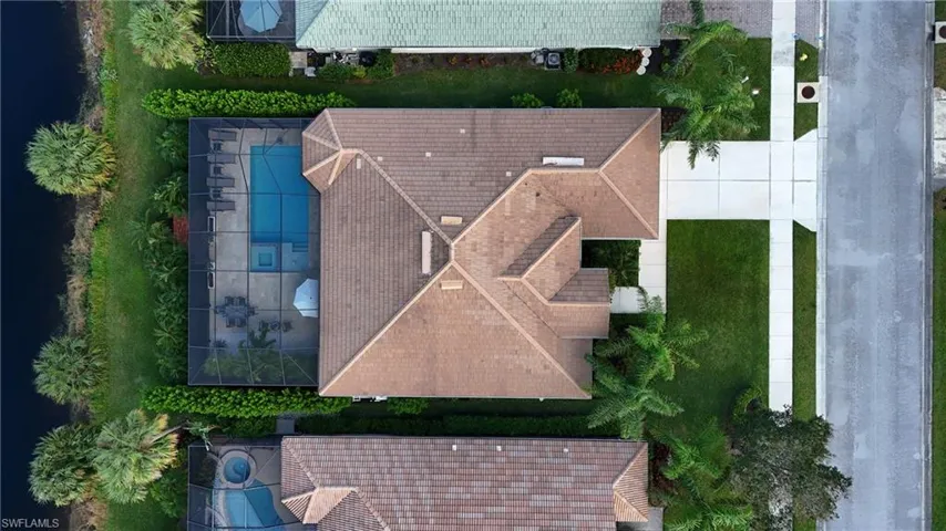 Aerial of home, showcasing screened in pool/jacuzzi and lake front views.