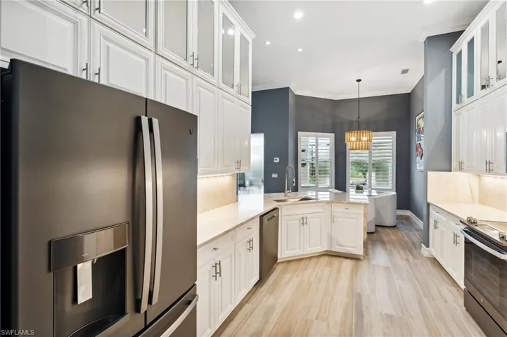 Kitchen featuring white cabinets, stainless steel appliances, hanging light fixtures, sink and more.