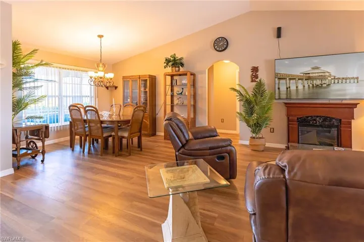 Living room with hardwood / wood-style floors, lofted ceiling, a high end fireplace, and a chandelier