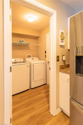 Clothes washing area with washing machine and dryer and light hardwood / wood-style floors