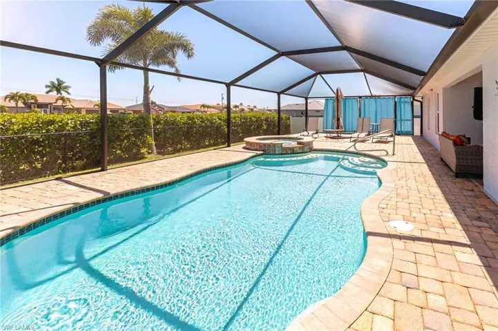 View of pool featuring a lanai, a patio area, and an in ground hot tub