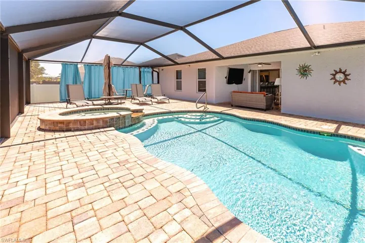 View of pool featuring a lanai, ceiling fan, a patio area, and an in ground hot tub