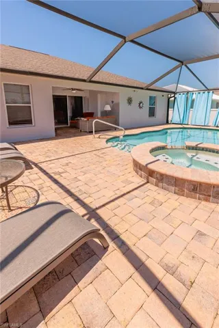 View of swimming pool with an in ground hot tub, a lanai, a patio area, and ceiling fan