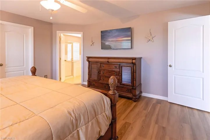 Bedroom featuring ensuite bathroom, ceiling fan, and wood-type flooring