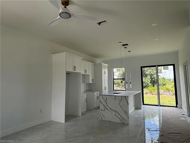 Kitchen featuring white cabinets, ceiling fan, a spacious island, decorative light fixtures, and recessed lighting