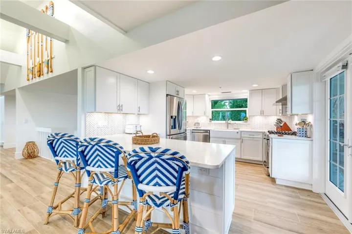 Kitchen featuring a peninsula, appliances with stainless steel finishes, white cabinets, light wood-style floors, and recessed lighting