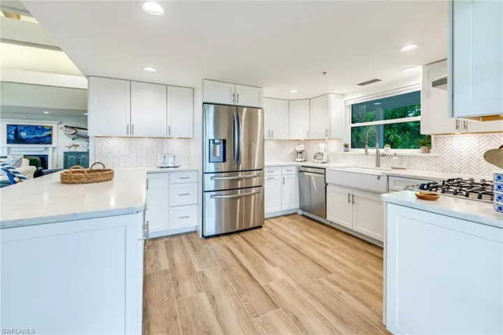Kitchen with appliances with stainless steel finishes, light stone countertops, white cabinetry, and recessed lighting