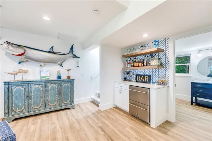 Indoor dry bar with open shelves, white cabinets, light wood finished floors, recessed lighting, and stainless steel dishwasher
