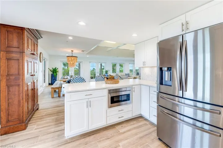 Kitchen featuring stainless steel appliances, a peninsula, white cabinets, wood tiled floors, and recessed lighting