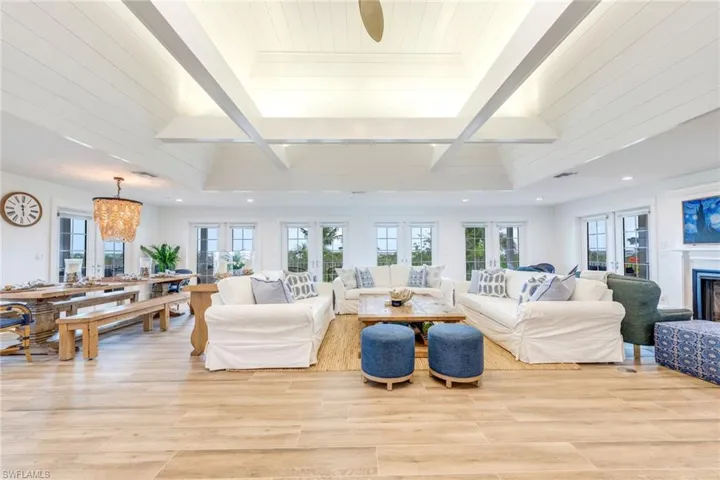 Living area with healthy amount of natural light, light wood finished floors, a fireplace, and beamed ceiling