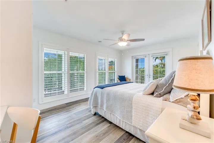 B1st floor bedroom with wood finished floors, ceiling fan, access to outside, and french doors