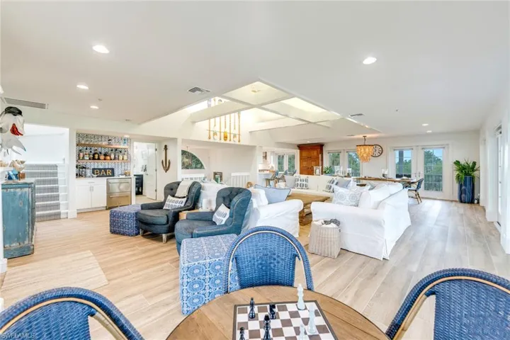 Living room featuring bar, recessed lighting, light wood-type flooring, and coffered ceiling