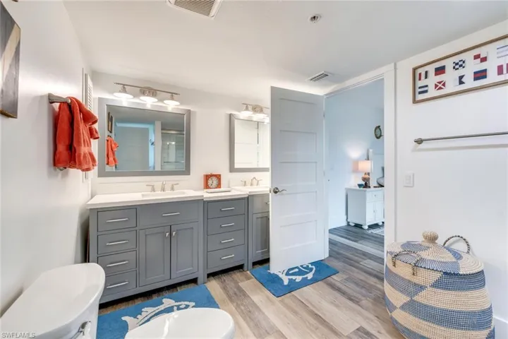 Full bathroom with double vanity, light wood-type flooring, and a shower with shower door