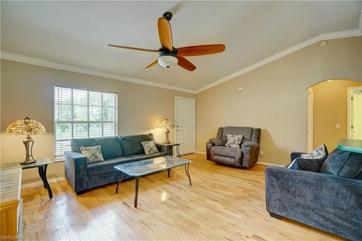 A large living room with vaulted ceilings, crown moulding, & hardwood floors