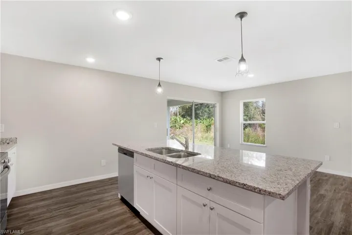 Kitchen featuring stainless steel appliances, sink, decorative light fixtures, and white cabinets