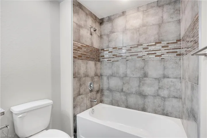 Bathroom featuring tiled shower / bath and toilet